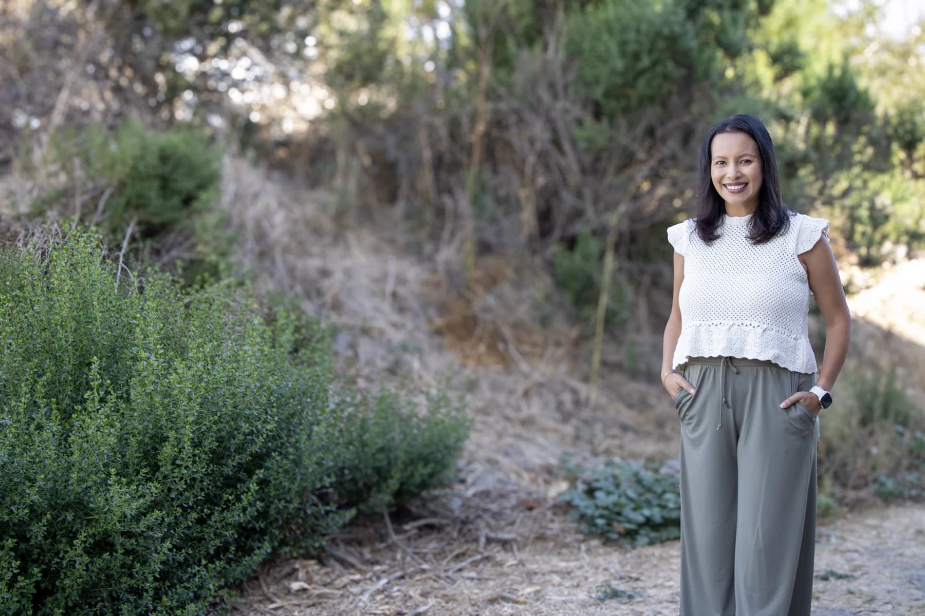 Selma Beirne smiling outdoors on a garden path, with open natural space around her.